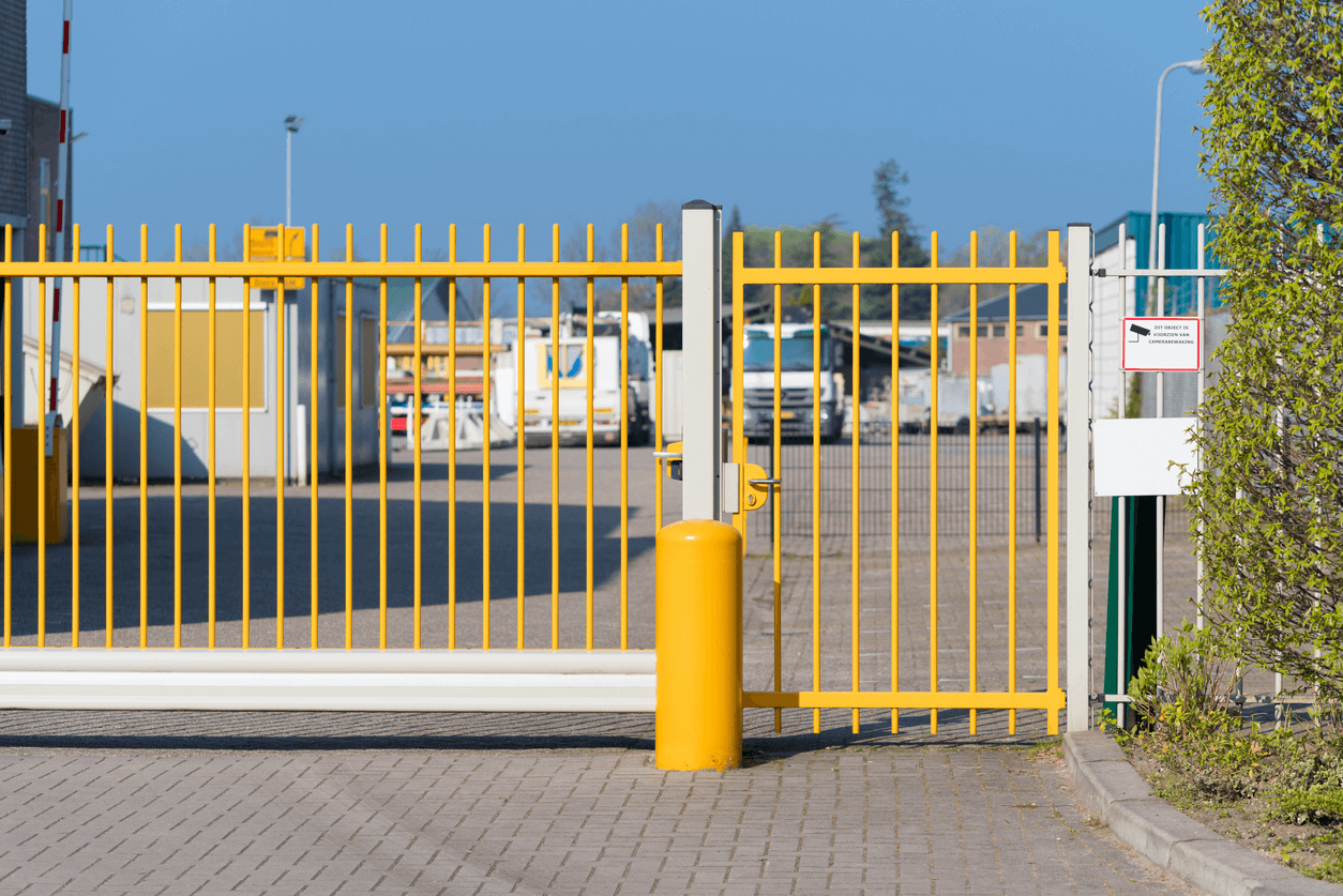 A gate made of yellow metal bars at the entrance of a large commercial facility.