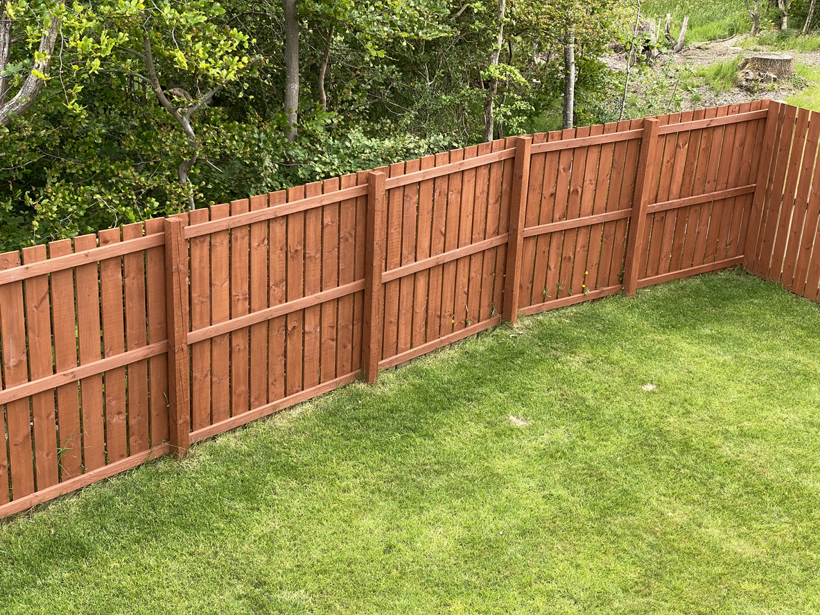 repaired wooden fence bordering a green lawn with woods in glenview.