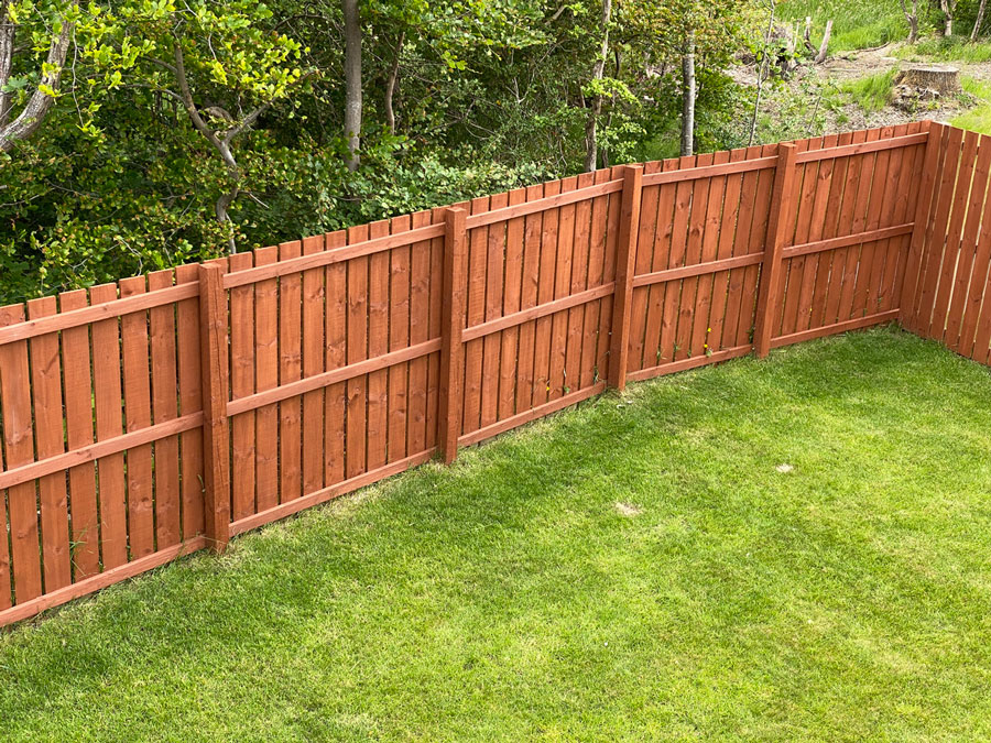 repaired wooden fence bordering a green lawn with woods in glenview.